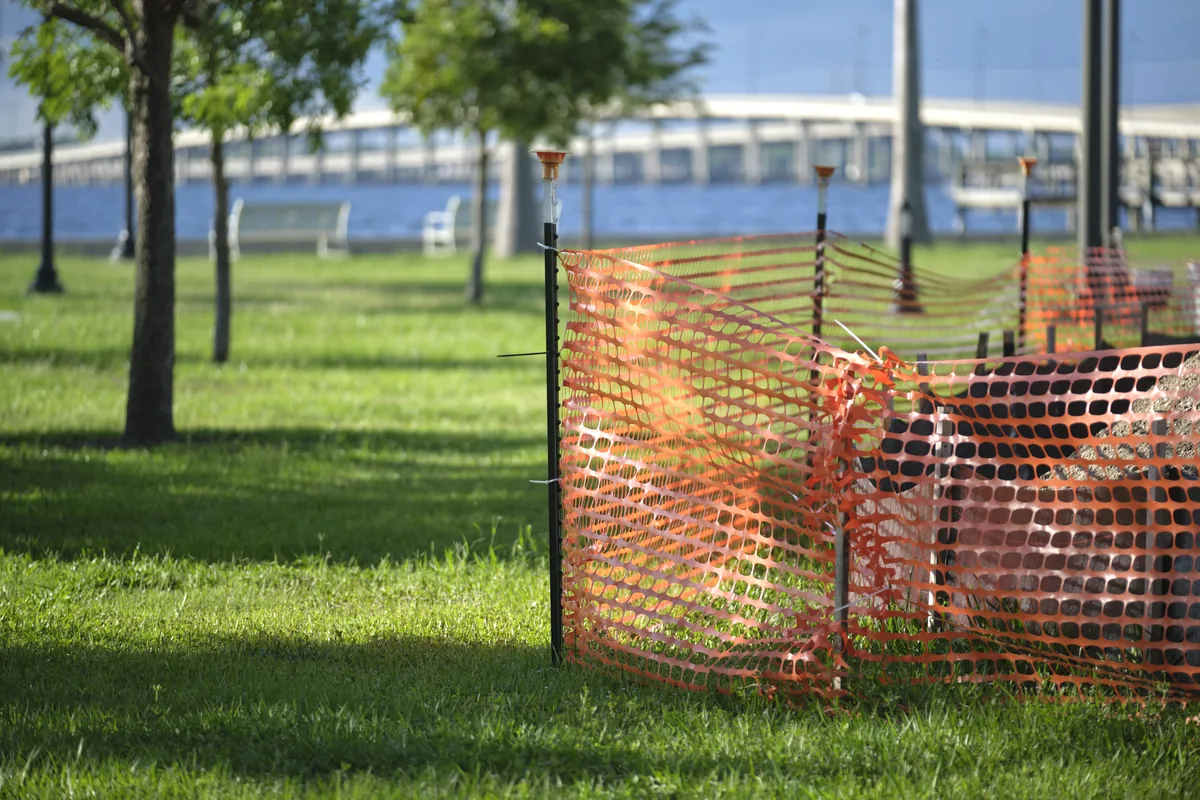 Orange safety fence set up around trees to protect them during site work